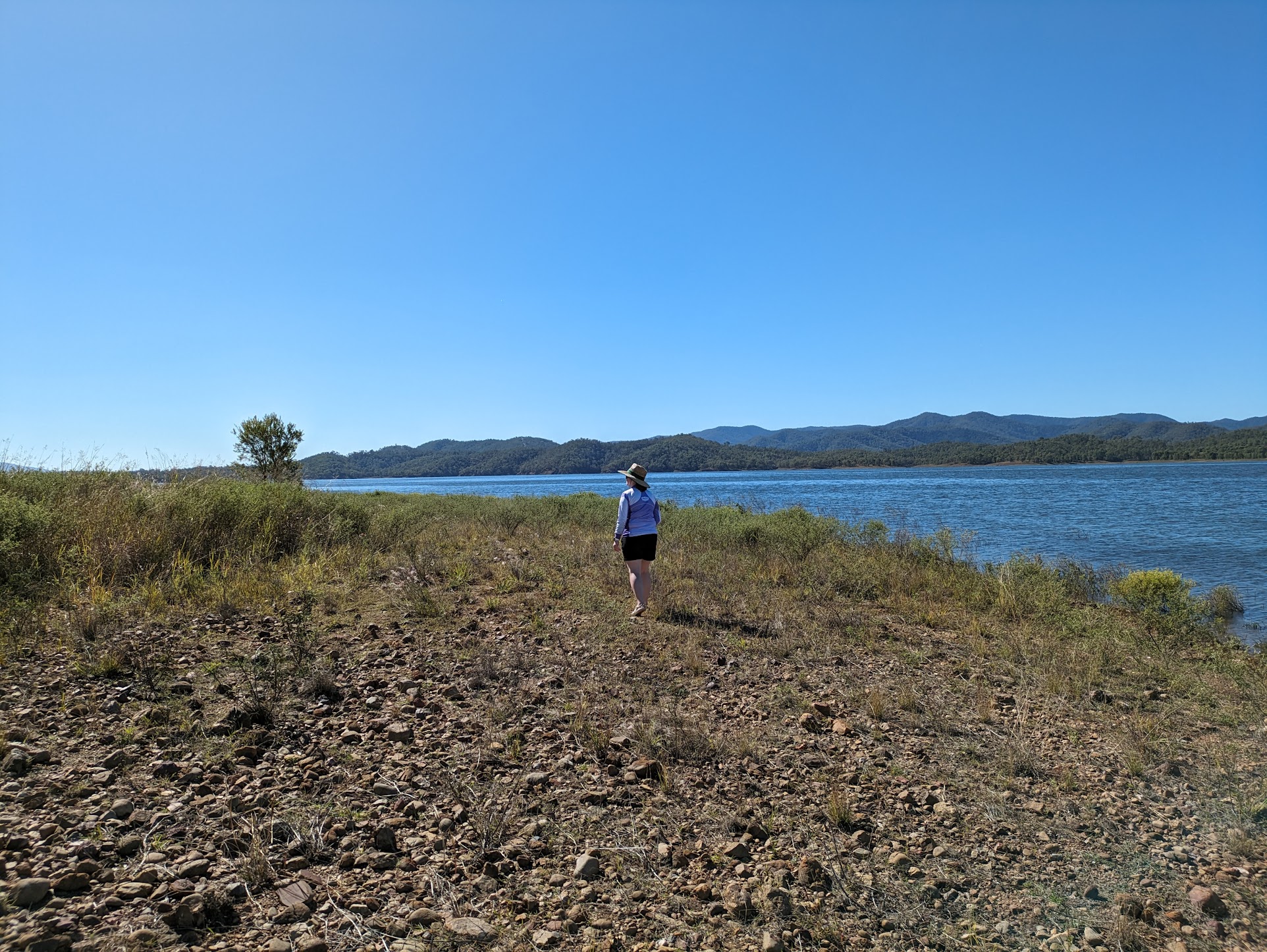 A photo of Michelle a short distance away along rocky ground.