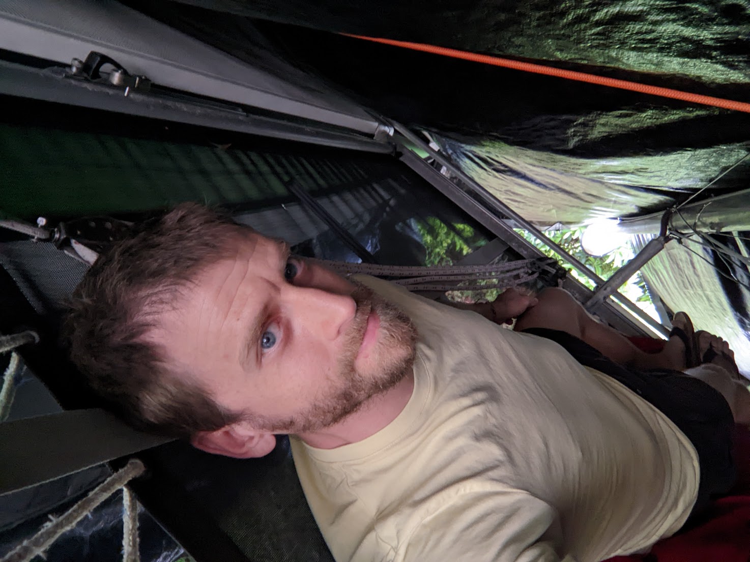 A photo of me laying on my back on the trampoline under a tarp.