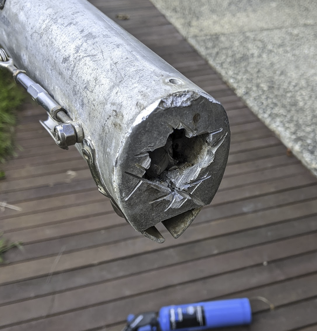 A photo of a ragged hole made of straight cuts in the base of the mast.