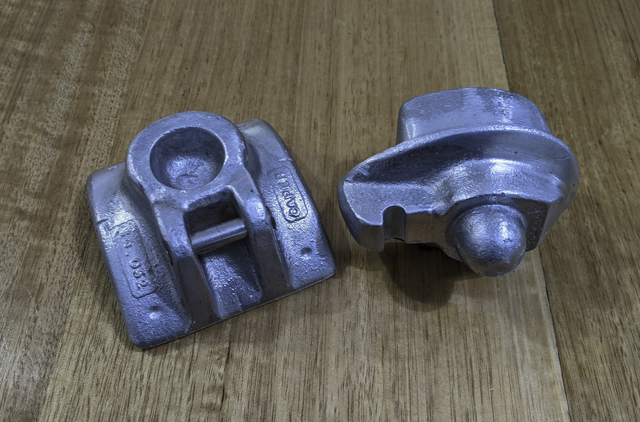A photo of two cast aluminium pieces sitting on a tabletop. One of the pieces has a dome, the other has a matching hollow pit.