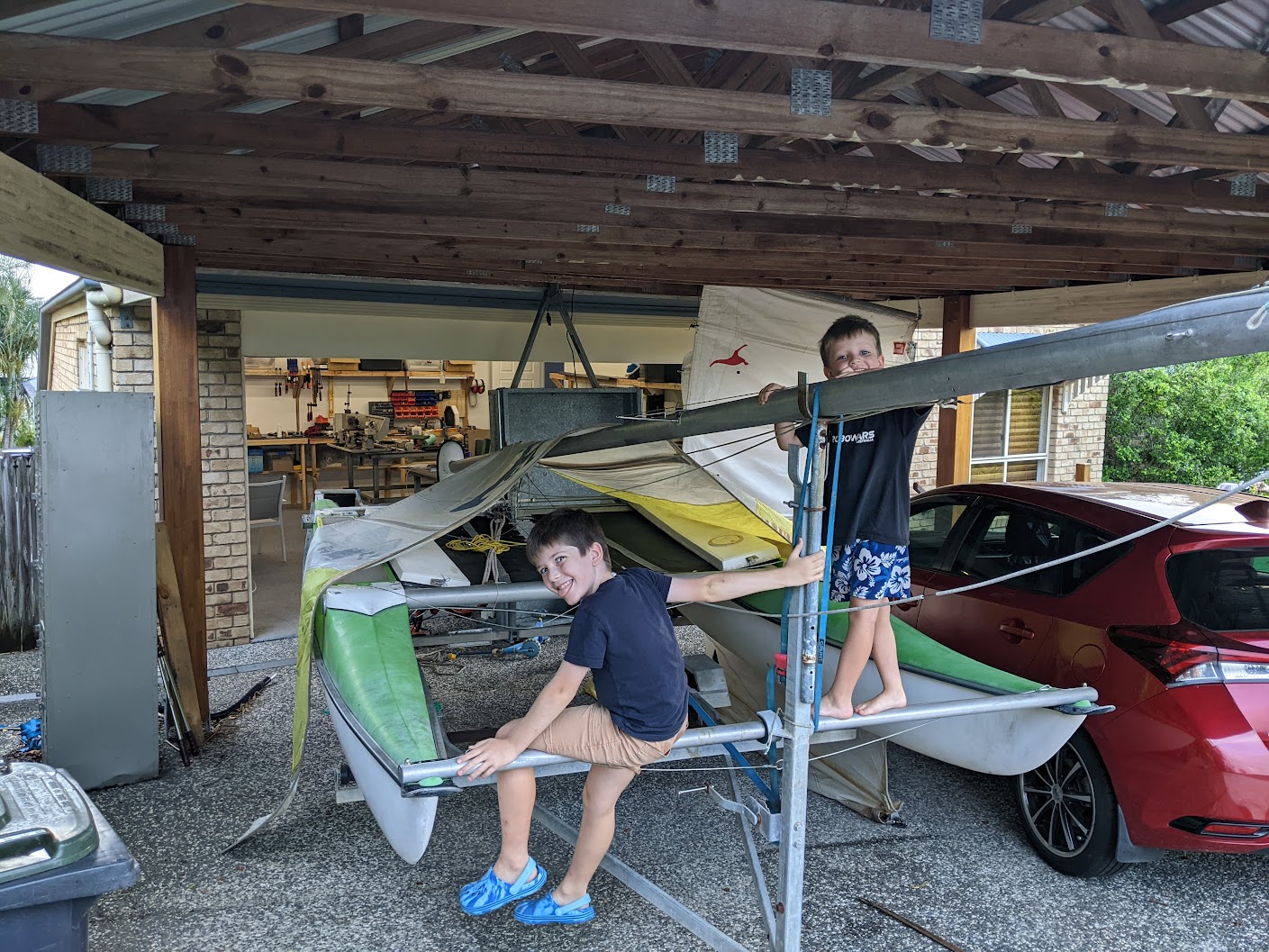 A photo of the boat under our carport with two boys climbing on it.