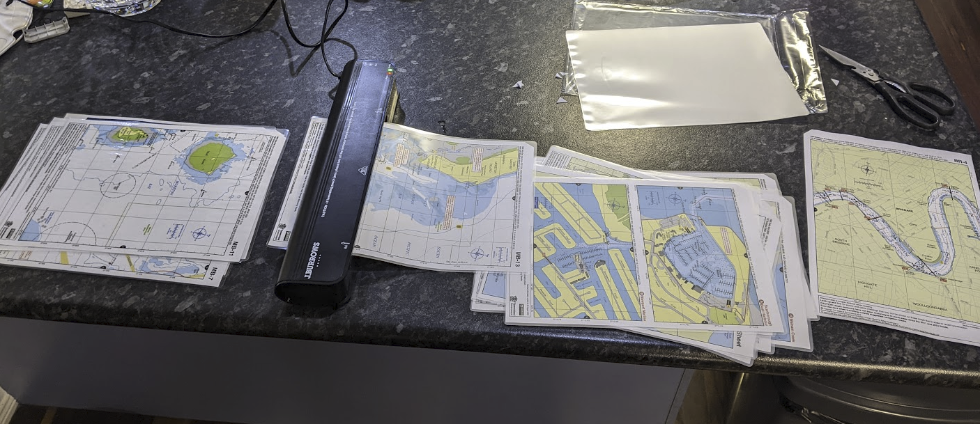 A photo of a pile of A4 printed charts being laminated on my kitchen bench.